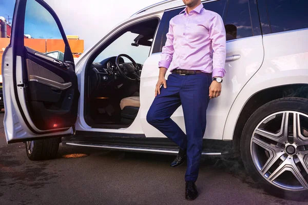 Parlak adam yol primli beyaz arabanın yanında duruyor, gökyüzünün yansıması, aynalar ve gözlüklerdeki bulutlar. Yüksek kalite fotoğraf