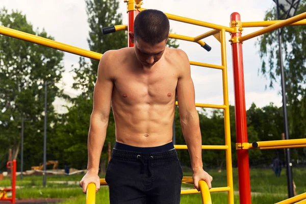 Strong man do street workout with difficult exercises and pose to camera