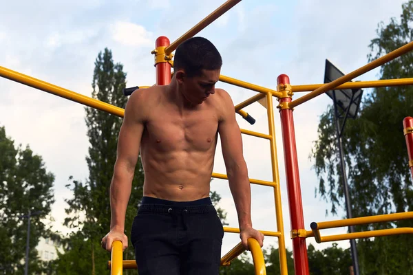 Strong man do street workout with difficult exercises and pose to camera