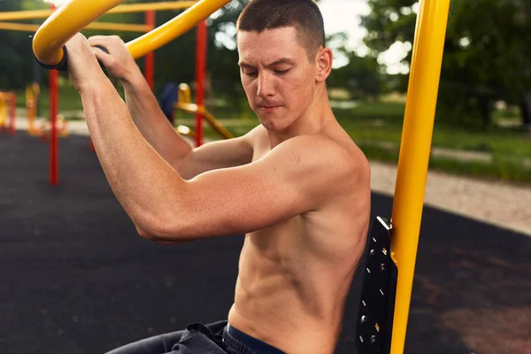 Strong man do street workout with difficult exercises and pose to camera