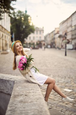 Genç sarışın kız pembe çiçekler ve şapka ile