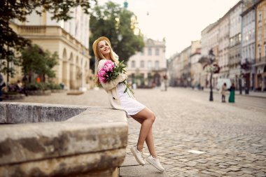 Genç sarışın kız pembe çiçekler ve şapka ile