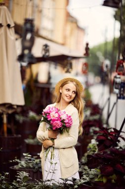 Genç sarışın kız pembe çiçekler ve şapka ile