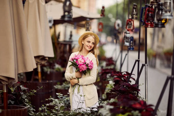 Ung Blond Flicka Med Rosa Blommor Och Hatt Stockfoto