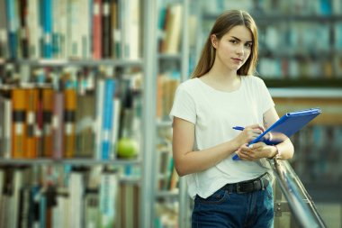 Güzel kız mavi kitap okumak ve kameraya gülümse