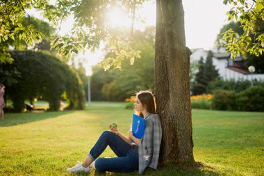 Park arka plan, gün batımı onu kitap ile güzel kız