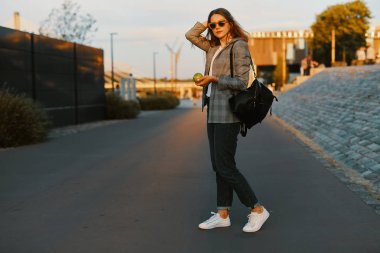 Moda kız yürüyüş günbatımı arka plan ile sokakta