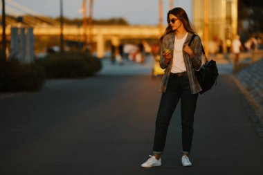 Moda kız yürüyüş günbatımı arka plan ile sokakta