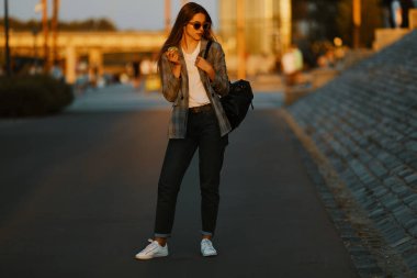Moda kız yürüyüş günbatımı arka plan ile sokakta