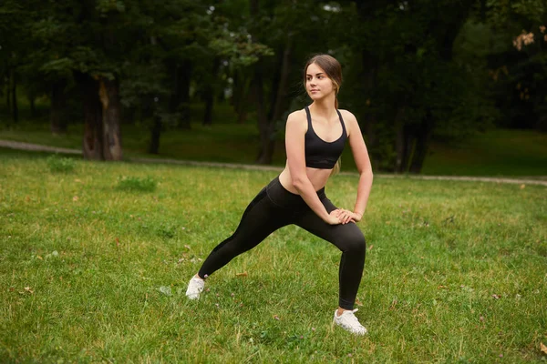 Menina Desportiva Agachamentos Grama — Fotografia de Stock