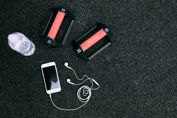 Set of water, phone, gloves, headphones on black background