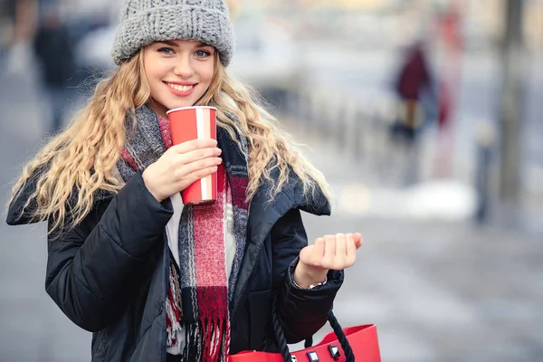 女性は 路上を歩きながら彼女のホット コーヒーを飲みます 冬のスタイリッシュな笑顔の女性の肖像画の服ホット コーヒーを飲みます 女性の冬のスタイル イメージ — ストック写真