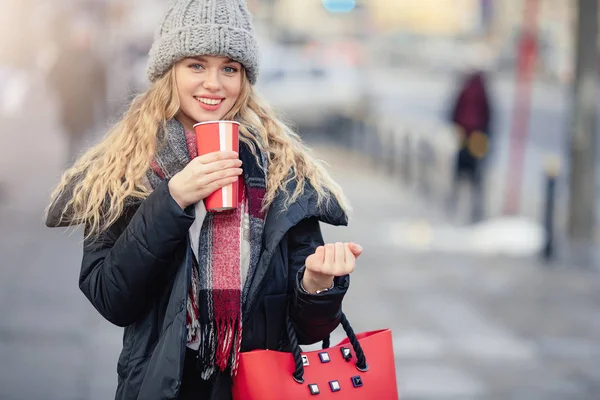 女性は 路上を歩きながら彼女のホット コーヒーを飲みます 冬のスタイリッシュな笑顔の女性の肖像画の服ホット コーヒーを飲みます 女性の冬のスタイル イメージ — ストック写真