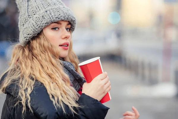 女人在街上散步时喝她的热咖啡 时尚的微笑的女人在冬季衣服的肖像喝热咖啡 女性冬季风格 图片仅供参考 — 图库照片