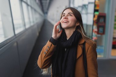 El bagajı yatılı okula gidiş ile smartphone üzerinde konuşurken Havaalanı iş kadını. Cep telefonuyla konuşma için kız.