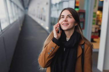 El bagajı yatılı okula gidiş ile smartphone üzerinde konuşurken Havaalanı iş kadını. Cep telefonuyla konuşma için kız.