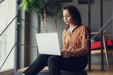 İş kadını ofiste merdivenlerde otur, iş üstünde laptop ve yeni fikirler hakkında düşünüyorum. İş için kopya alanı dizüstü bilgisayar kullanan kız