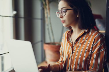 İşkadını giyim gözlük ofis, iş üstünde laptop ve kalem ile yeni fikirler hakkında düşünüyorum. İş için kopya alanı dizüstü bilgisayar kullanan kız