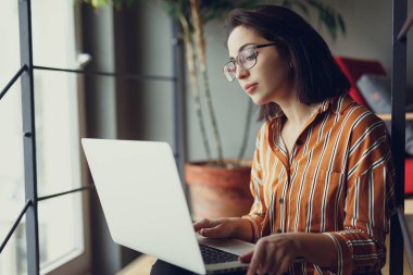 İşkadını giyim gözlük ofis, iş üstünde laptop ve kalem ile yeni fikirler hakkında düşünüyorum. İş için kopya alanı dizüstü bilgisayar kullanan kız