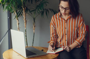 İşkadını giyim gözlük ofis, iş üstünde laptop ve kalem ile yeni fikirler hakkında düşünüyorum. İş için kopya alanı dizüstü bilgisayar kullanan kız