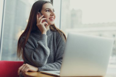 Görünüm. Oturan genç iş kadını masa ve onun telefon laptop bakarken konuşmak. Café'de çalışan kadın. Blogger. -Görüntü