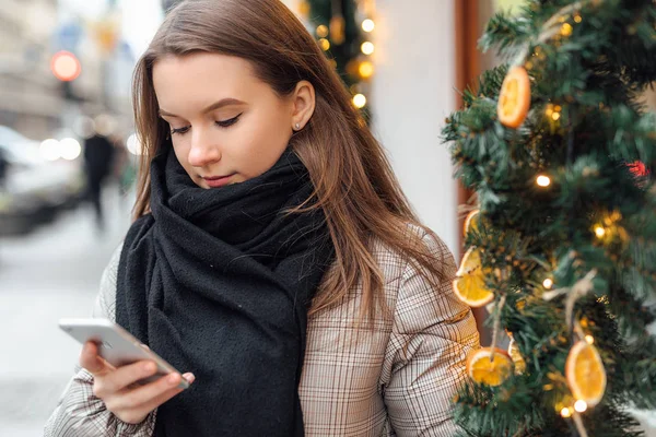 Happy girl walk in the street and talk at her phone with happy face. Wear black scarf. Winter, autumn outfit.