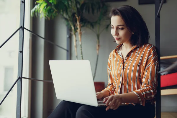 Businesswoman sit on stairs in office, work on laptop and think about new ideas. Girl using laptop for work, copy space