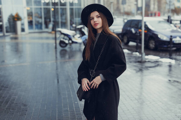 Young fashion woman walking on the city street wear black hat look around and smile to camera. Copy space. - Image