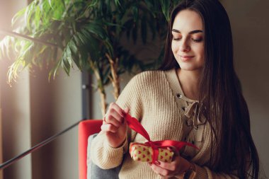 Güzel esmer kadın üzerinde flor otur ve onun Noel hediyesi açık pencerenin yanında mutlu yüz ile. -Görüntü