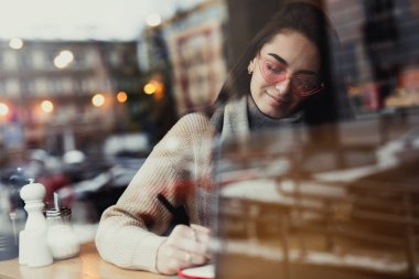 Oldukça esmer kadın onun işi kafede, gözlük ve dizüstü pencerenin yakınındaki bir sohbet. -Görüntü