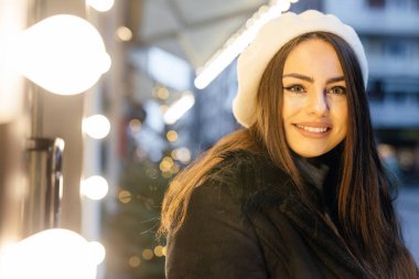 Güzel kız sokak giyim siyah şapka üzerinde durmak, pencere mağazasında bakar ve komik ifadeler yüzünde. -Görüntü
