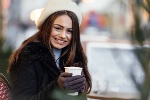 在多云的天气里 漂亮的女人站在大街上喝着一杯热咖啡 一边喝着咖啡 一边对着镜头微笑 一边在电话里与复制空间背景交谈 图片仅供参考 — 图库照片