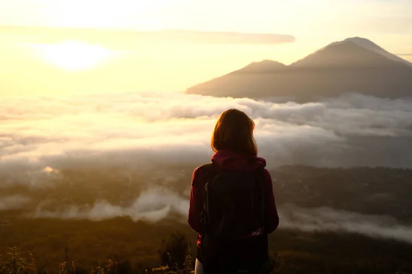 Mladá žena batohem sledování východu slunce a volcanoe na ostrově Bali Stock Snímky