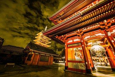 Tokyo, Japonya - 25 Kasım 2012: Tokyo 'daki Sensoji Tapınağı' na hayran olan ziyaretçiler, gece gökyüzüne karşı aydınlatılmış, parlak renkler ve eşsiz bir mimari sergiliyorlar..