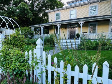 Perry Limanı, Kanada - 12 Ağustos 2023 Port Perry 'de bir yaz günü beyaz çit ve canlı bir bahçe gösteren büyüleyici bir ev.