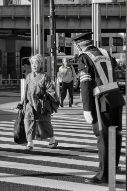 Tokyo, Japonya - 26 Kasım 2012: Geleneksel giysili yaşlı bir kadın, gün içinde Tokyo 'da ona rehberlik ederken neşeyle caddeyi geçiyor.