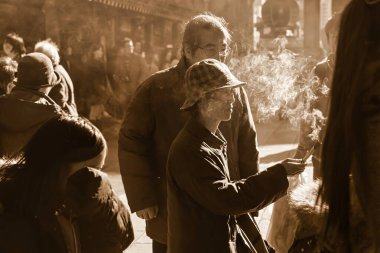 Tokyo, Japonya - 26 Kasım 2012: Yaşlı bir adam tütsü yakarken kalabalık sokak satıcıları ve turistlerle çevrili olarak Asakusa Tokyo 'da toplandı.