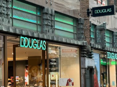 den haag, Hollanda - 18 Ekim 2024: Lahey 'deki Douglas mağazası, şık yeşil tabelalarla aydınlatılmış modern bir iç mekan sergiliyor