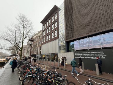 amthe, Hollanda - 15 Ocak 2025: İnsanlar bisiklet ve Anne Frank House Müzesi ile birlikte geleneksel ve çağdaş mimari bir karışım ile cadde boyunca yürüyorlar