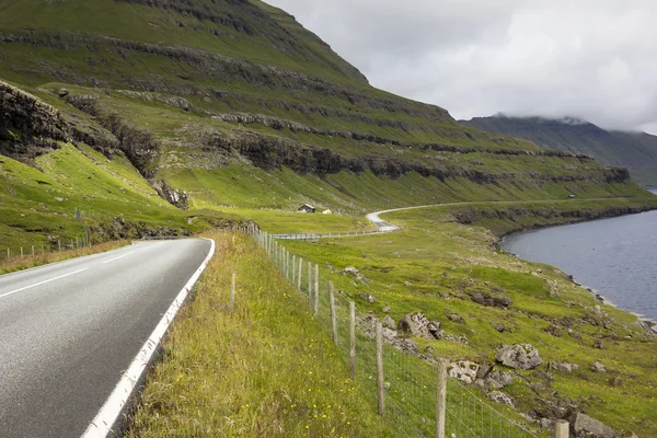 Faroe Adaları tipik bir durumda. Bir yol dağların altında ve fiyortları yukarıda Rüzgarlar.