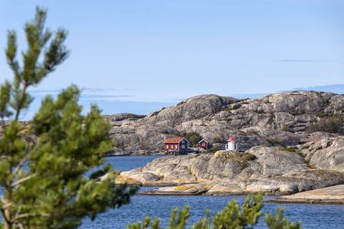 Kabinler, tekneler ve skerry kıyısında küçük bir deniz feneri