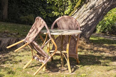 Güzel bir bahçede iki hasır sandalye ve bir masa standı