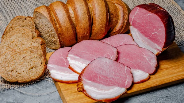smoked meat and bread with bran on wooden background