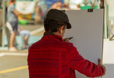 Adam beyaz kağıt Street üzerinde portre çizer.