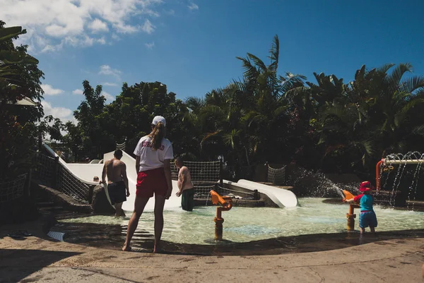 Female lifeguard standing near kids swimming pool.