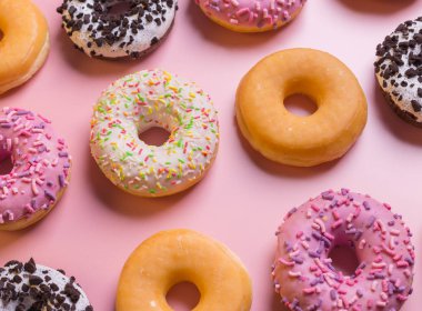Pembe bir arka plan üzerinde birçok renkli Donuts üstten görünüm.