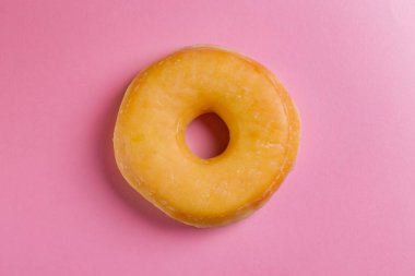 Pembe bir arka plan üzerinde tek yuvarlak çörek.