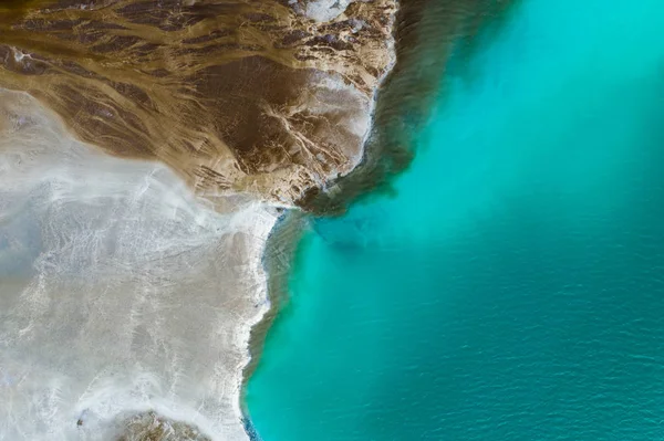 Top down view on rich mineral waste flow from power plant to emerald lake.