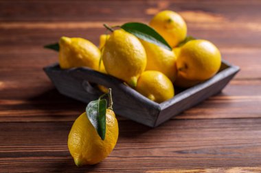 Ahşap masa yapraklarda ile taze sulu sarı limon.