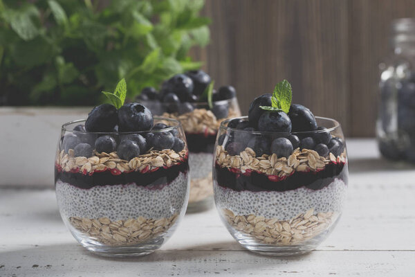 Light dessert of chia pudding with blueberry, oats and fresh jam, served in thin glass. 